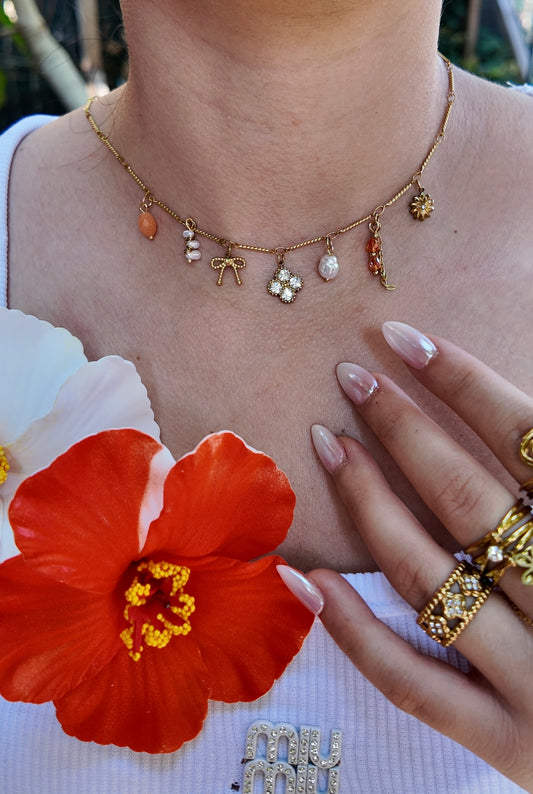 Néréa - Collier doré à charms perles oranges, nœud et fleur strassée